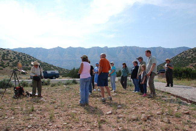 An artist painting the park with several visitors watching