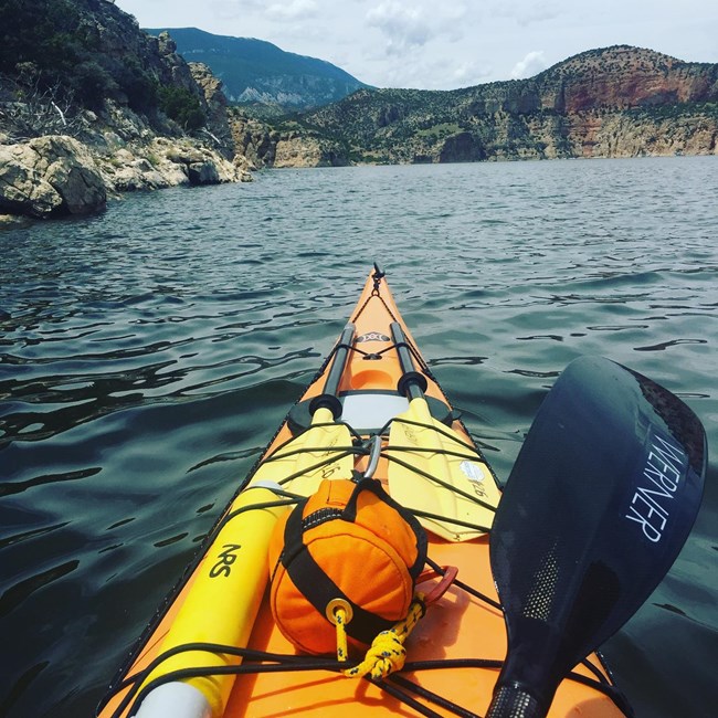 Orange kayak paddling in open water.