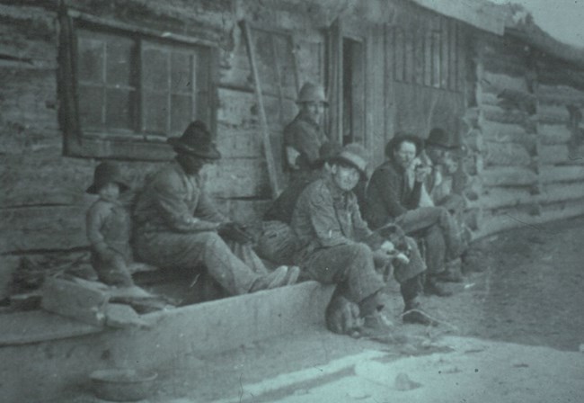 Cowhands seated in front of the west cabin of the ML bunkhouse