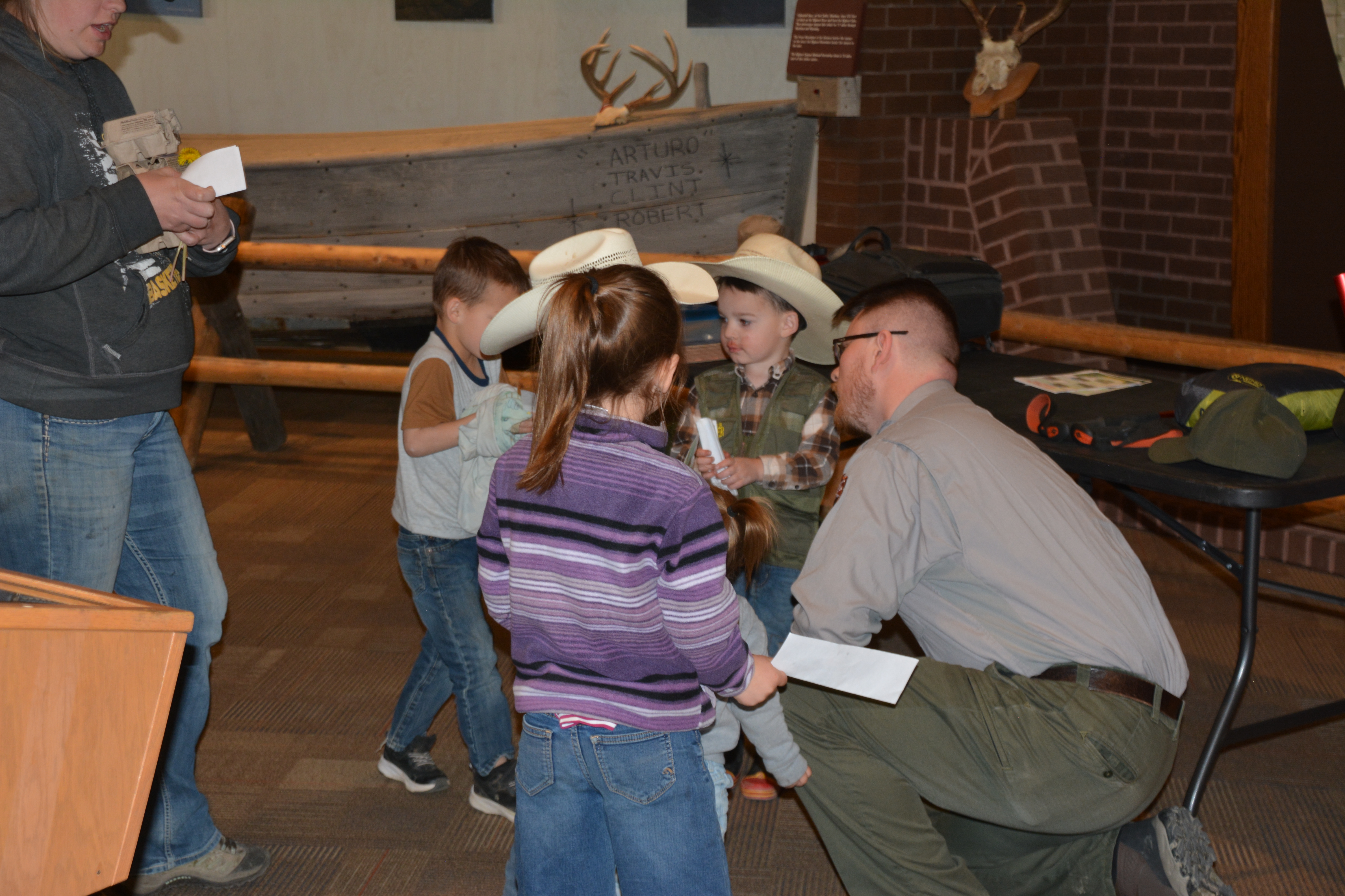 A ranger kneeling on the ground to swear in a group of 5 Junior Rangers.