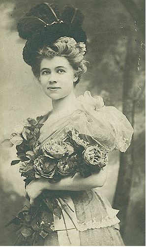 A young Caroline Lockhart holding a bouquet of flowers wearing a dress.
