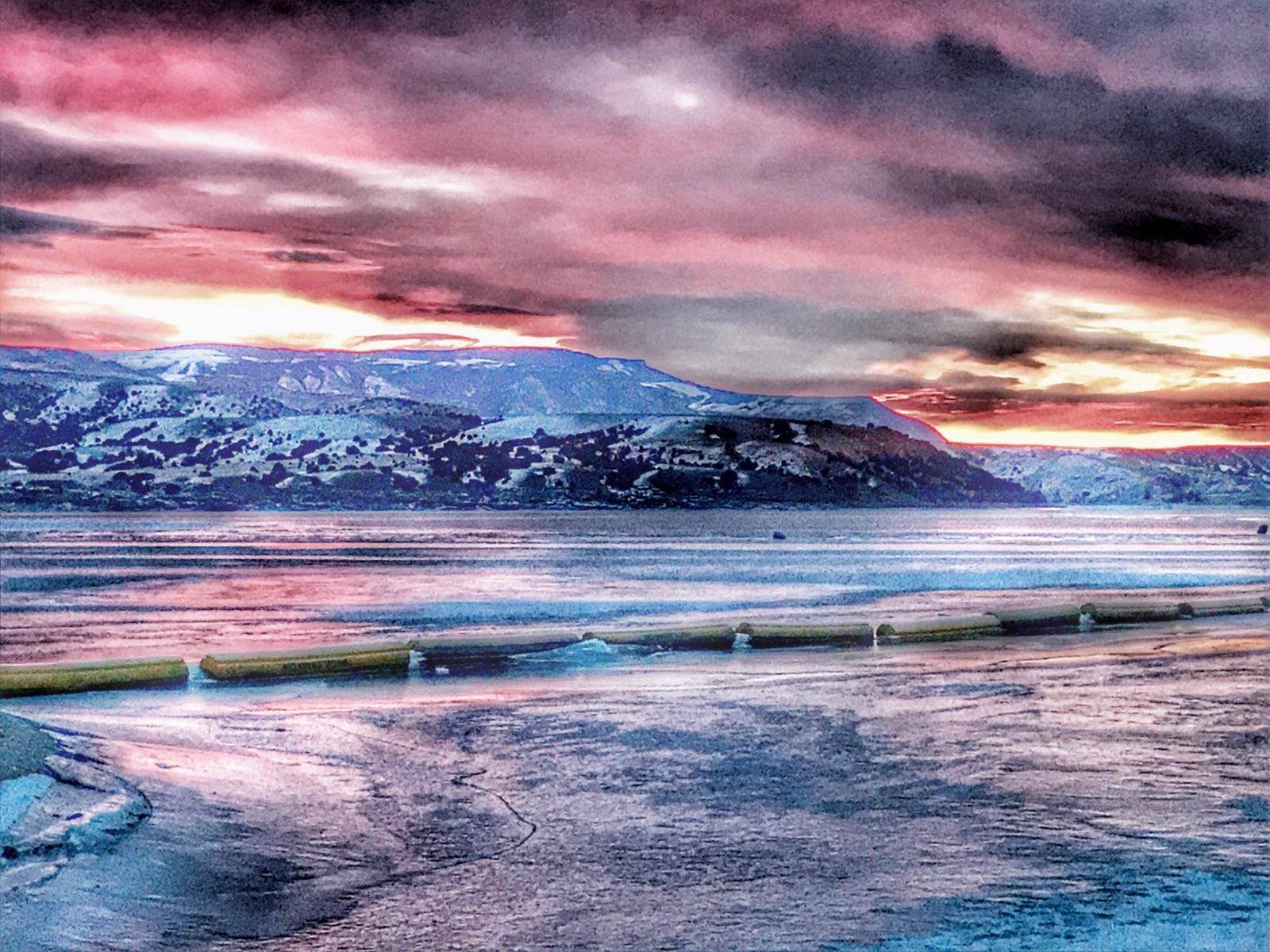 Ice at Horseshoe Bend Sunrise over an iced over lake with hills in the background.