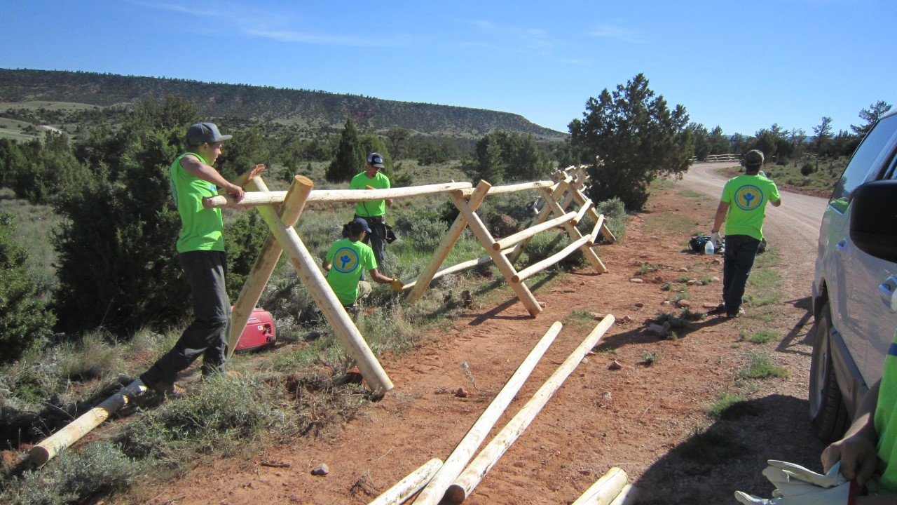 YCC Building Fence Several teenagers in bright green shirts assemble a bucking rail fence.