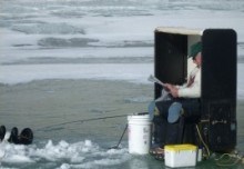 Ice fisherman waiting for a strike on his line Ice fisherman waiting for a strike on his line
