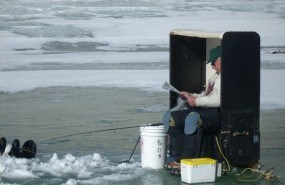 A ice fisherman sinks his line and waits.