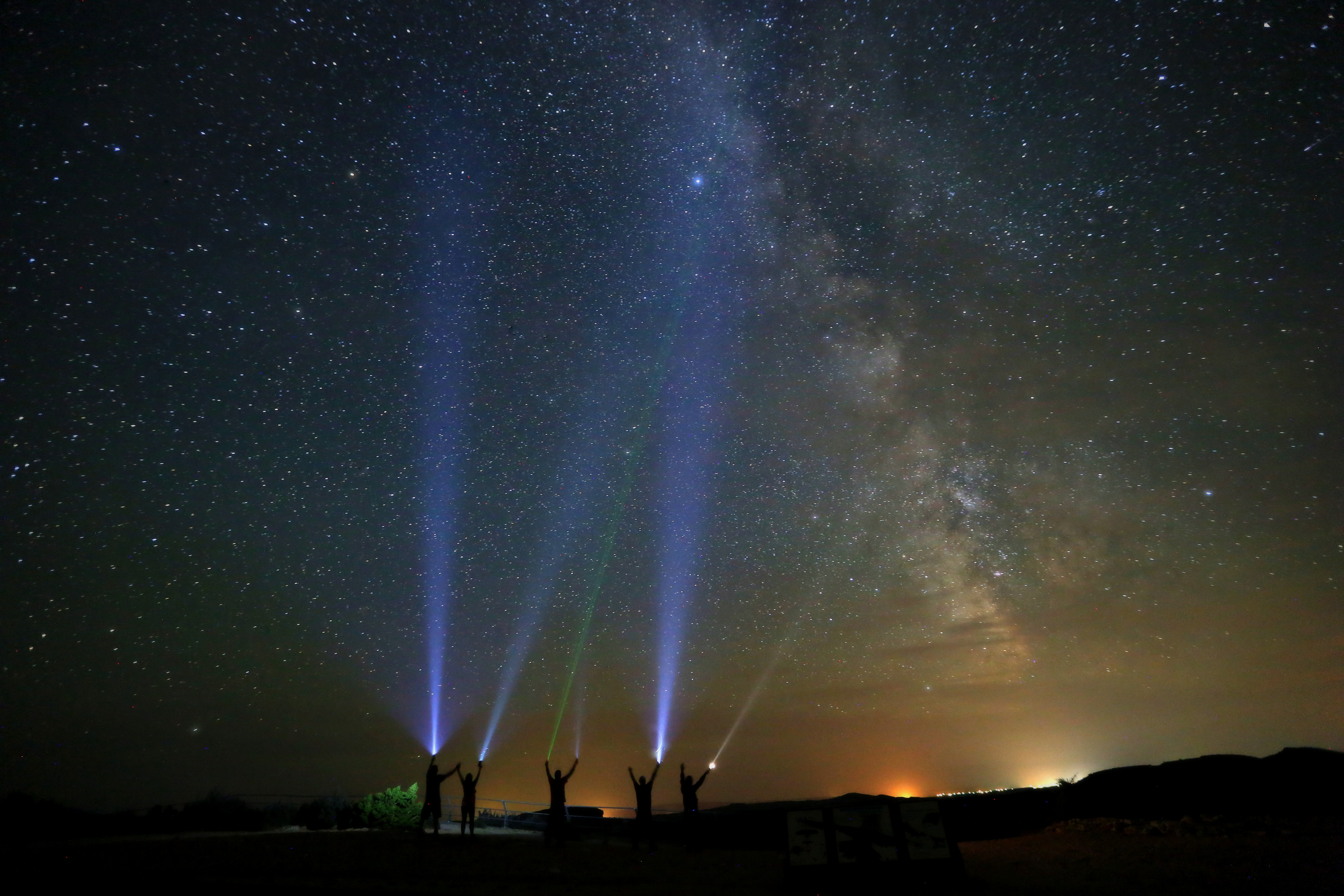 5 people shine flashlights into the night sky at Devil Canyon Overlook.