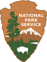 An arrowhead with the words National Park Service in the upper right corner. A tree, mountain, lake, and bison are below and to the right of the words.
