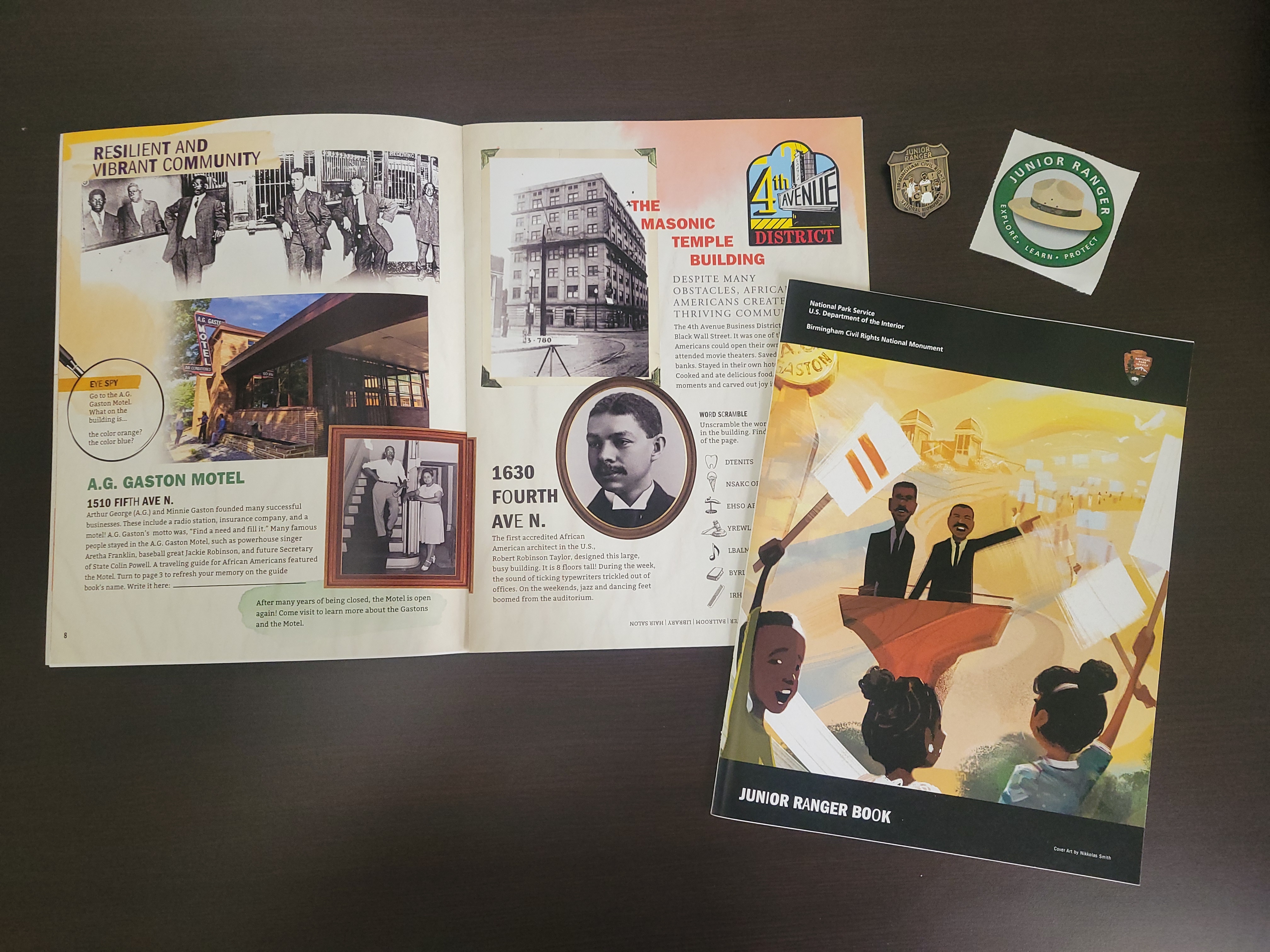 A junior ranger book sits open with another closed on top. Above is a sticker and Junior Ranger Badge.
