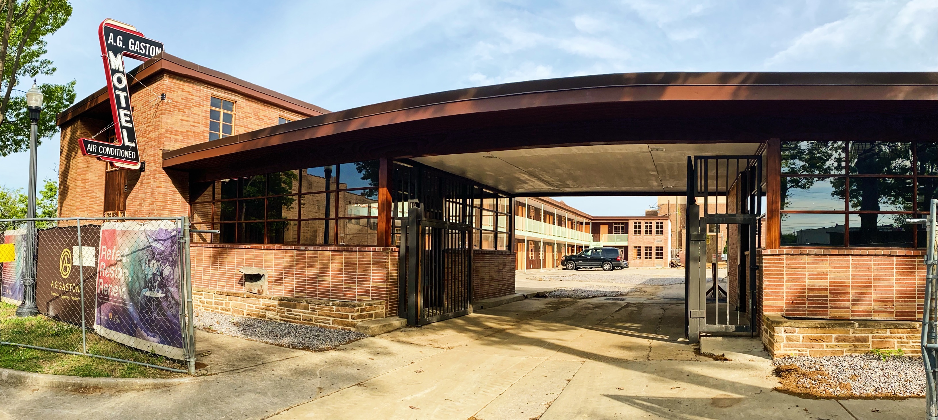 A red, two-story brick hotel with covered drive-in entrance and cars in parking area