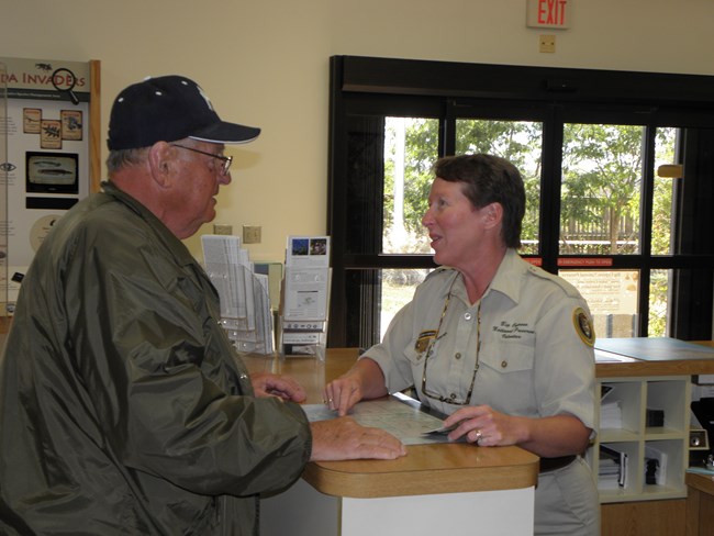 Uniformed volunteer at desk helps visitor