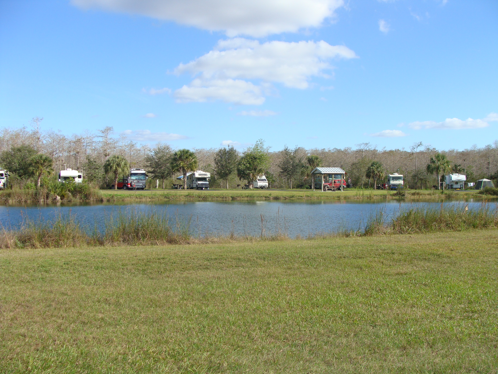 View across lake to grassy camping area with RVs and tents