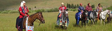 Nez Perce people in full regalia on decorated horses.