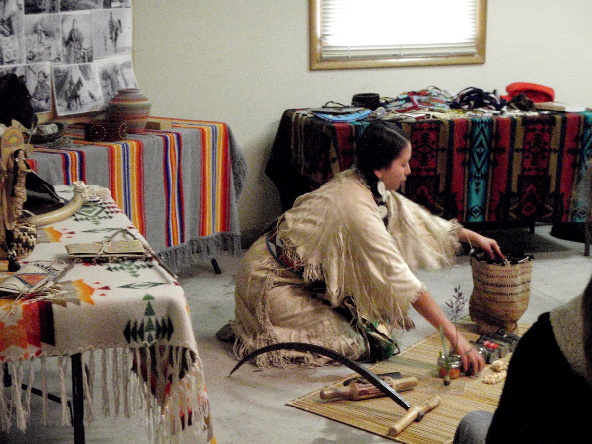 Cultural Demonstrators Wanted woman in traditional Nez Perce clothing sits on floor with her cultural items.