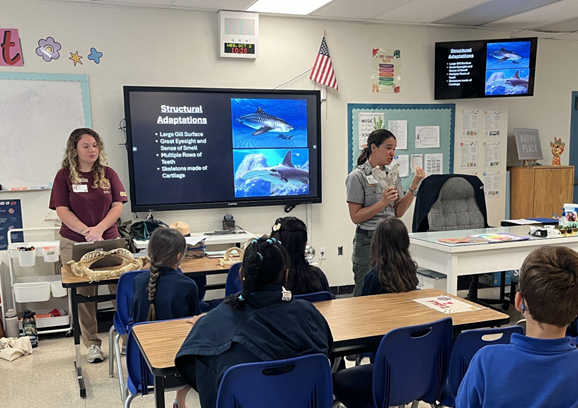 A ranger holds up a skull while presenting about adaptations.