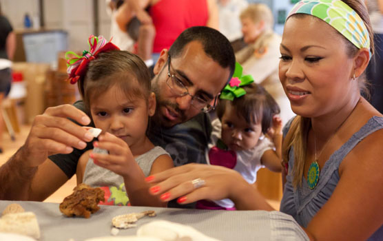 Dad, daughter and mom closely examine a piece of coral.