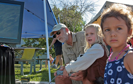 A park volunteer assists a youngster in operating a robot.