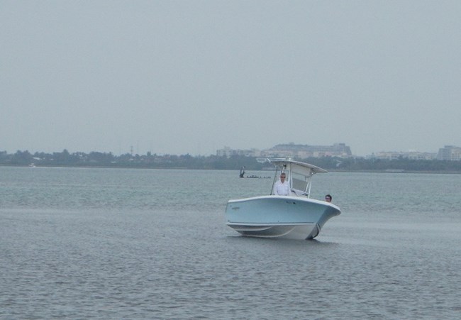 Boat which has come almost completely out of the water resting on the sea bottom with two people onboard