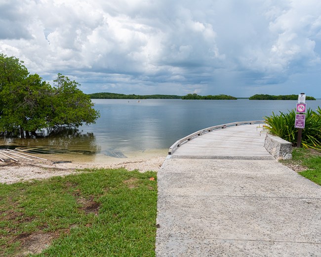 A trail veers off to the right and a canoe launch is to the left. Ocean and grey skies above