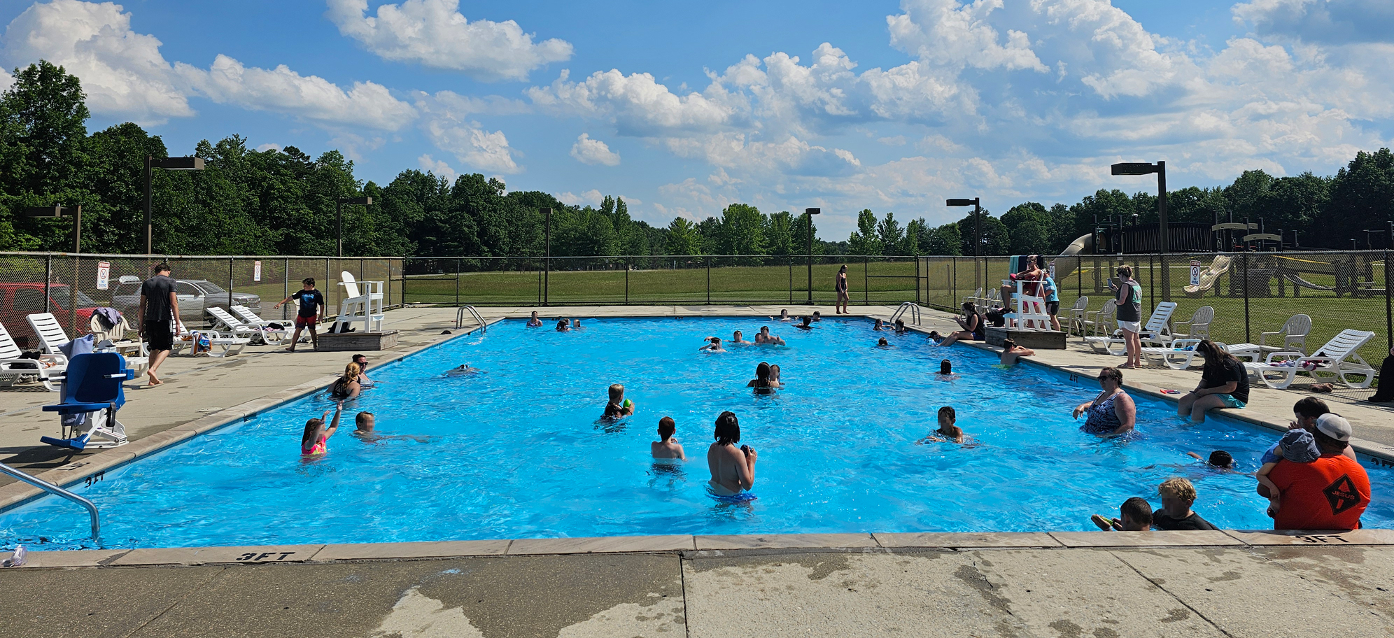 Day-at-the-pool A group of people swimming in a pool on a sunny day.