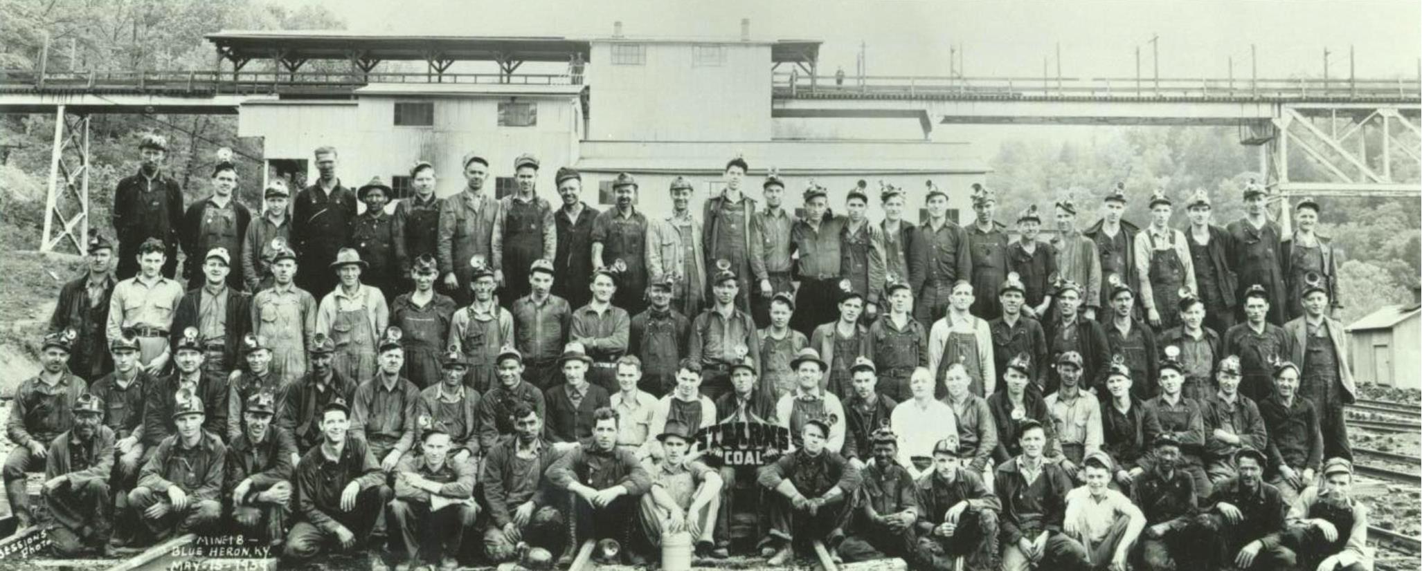 black and white photo of mine workers with Tipple Bridge in background