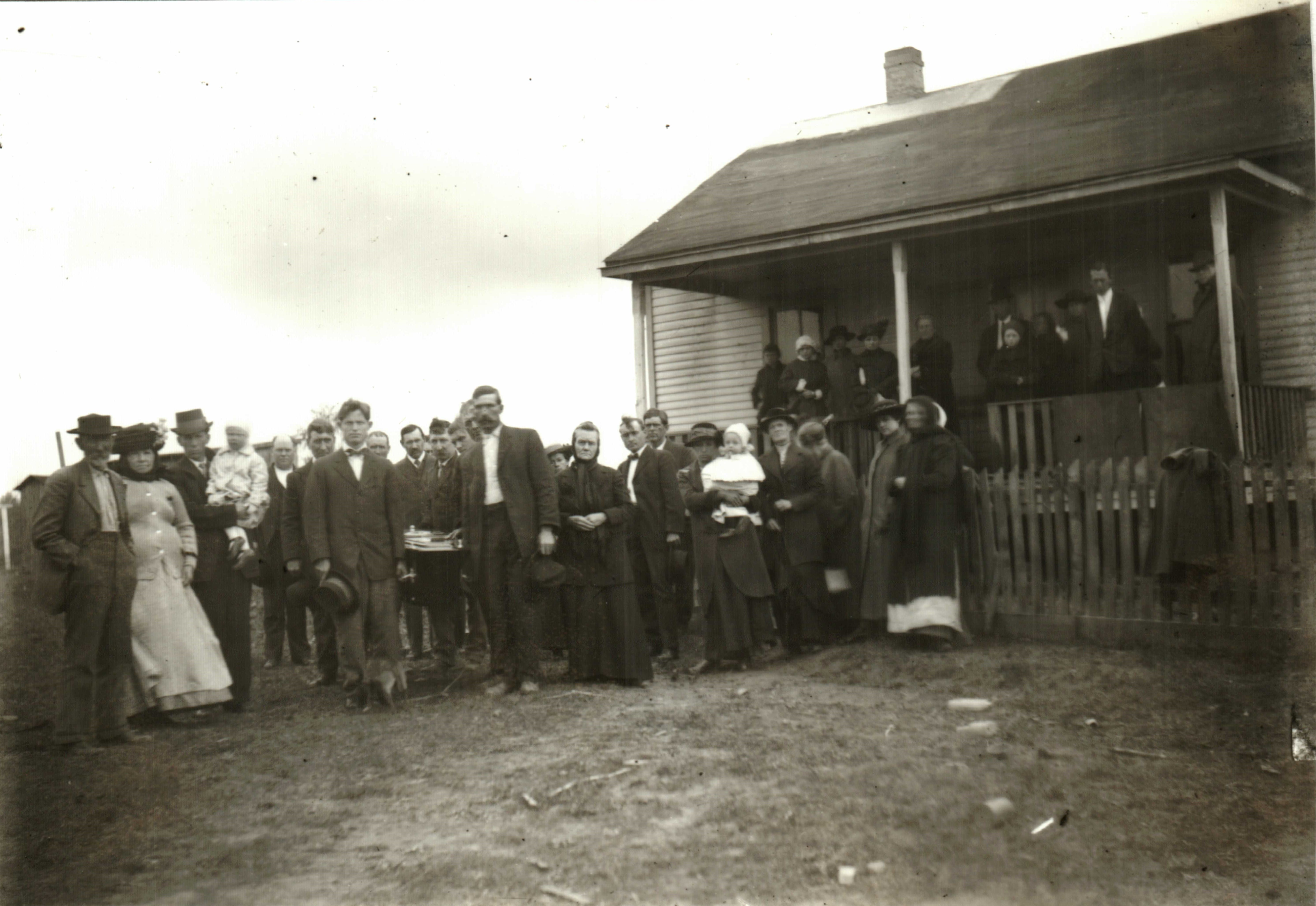 A black and white photo with a group of people at a funeral.
