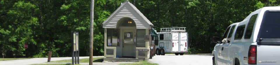 White truck heads towards small entrance station building.