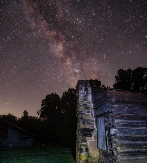 wooden cabin with dark skies and stars