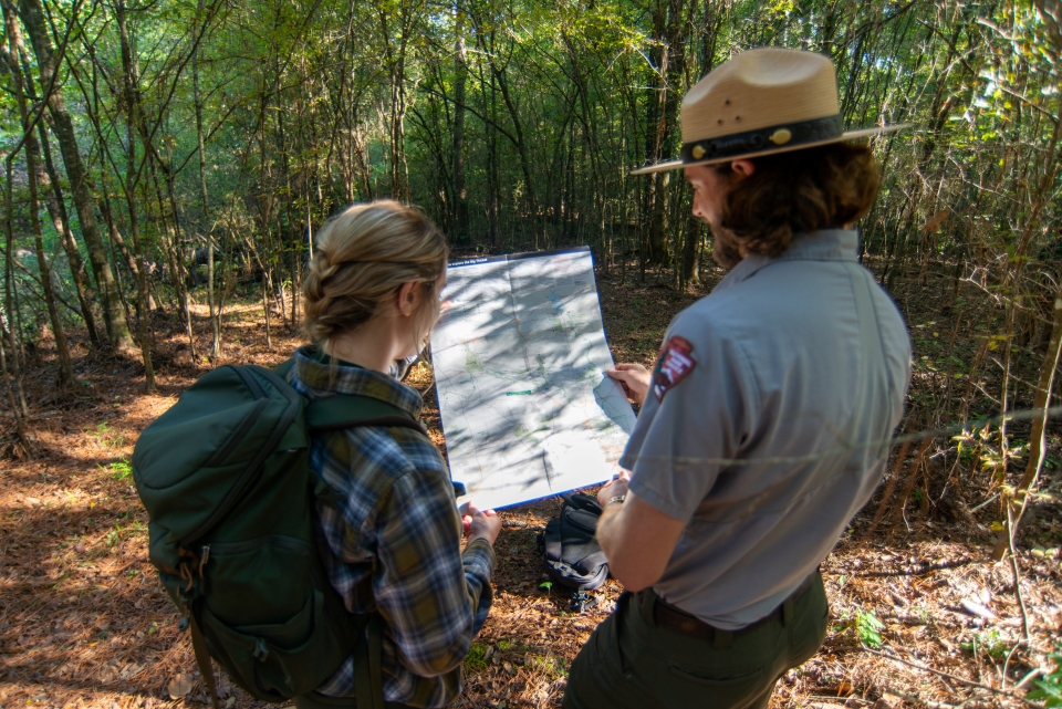 Hiker and Park Ranger a hiker and a park ranger looking at a park map while standing on a trail in the forest