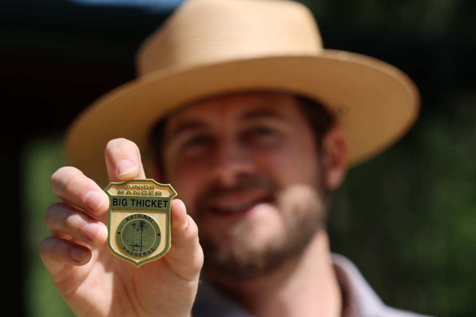 close up of a Big Thicket junior ranger badge being held by a park ranger
