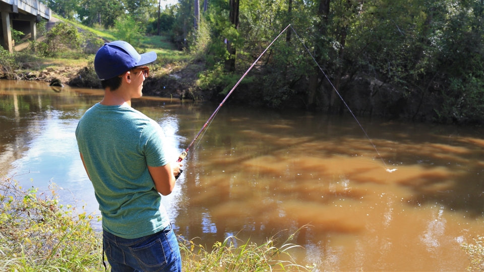 person fishing along the bank a creek