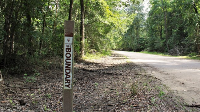 white boundary sign along rural road in the woods