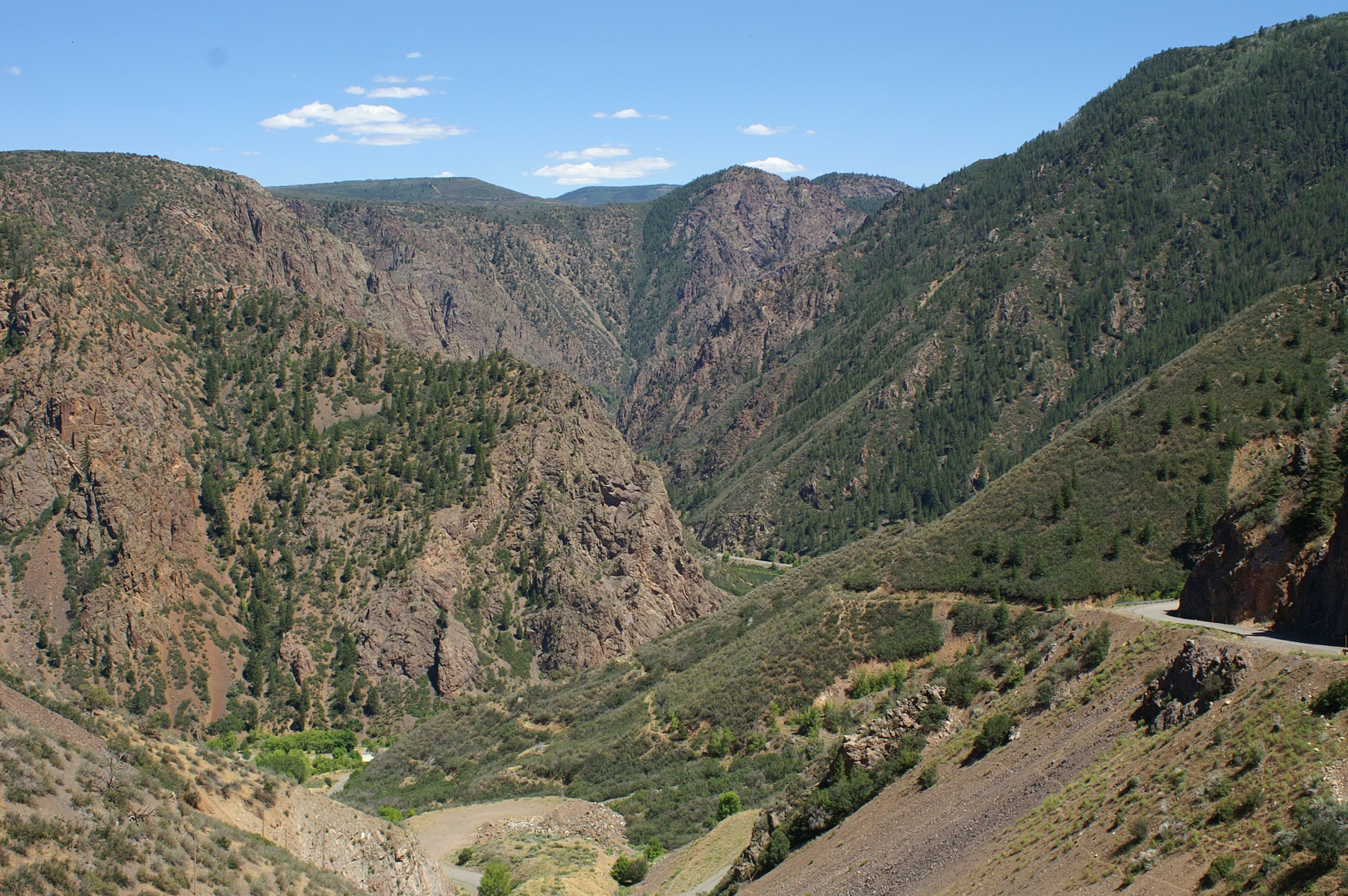 narrow, winding road descends into a deep canyon of gray and glittery rock