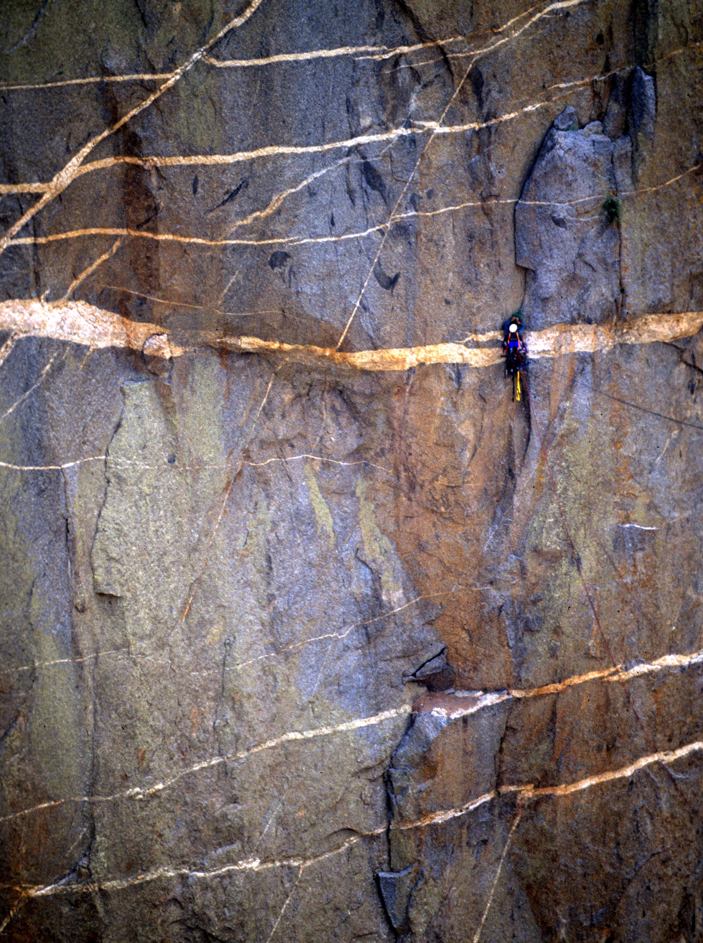 Rock climber ascending the steep granite walls of Black Canyon of the Gunnison with dramatic shadows and towering vertical cliff faces