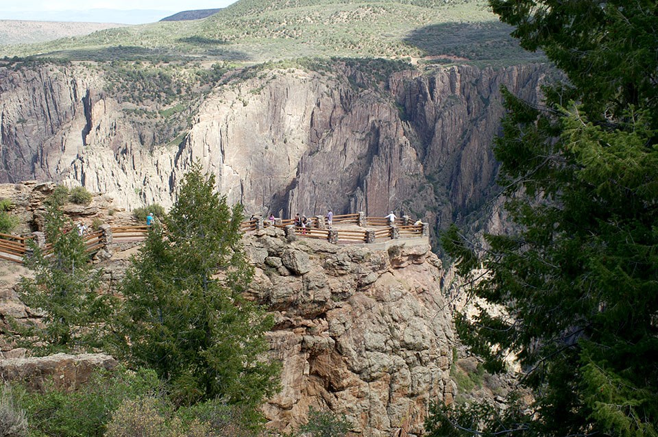 people at an overlook on a peninsula jutting out into Black Canyon, with the canyon in the background