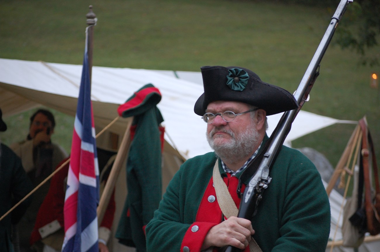 Man in historic clothing with a rifle in his hand.