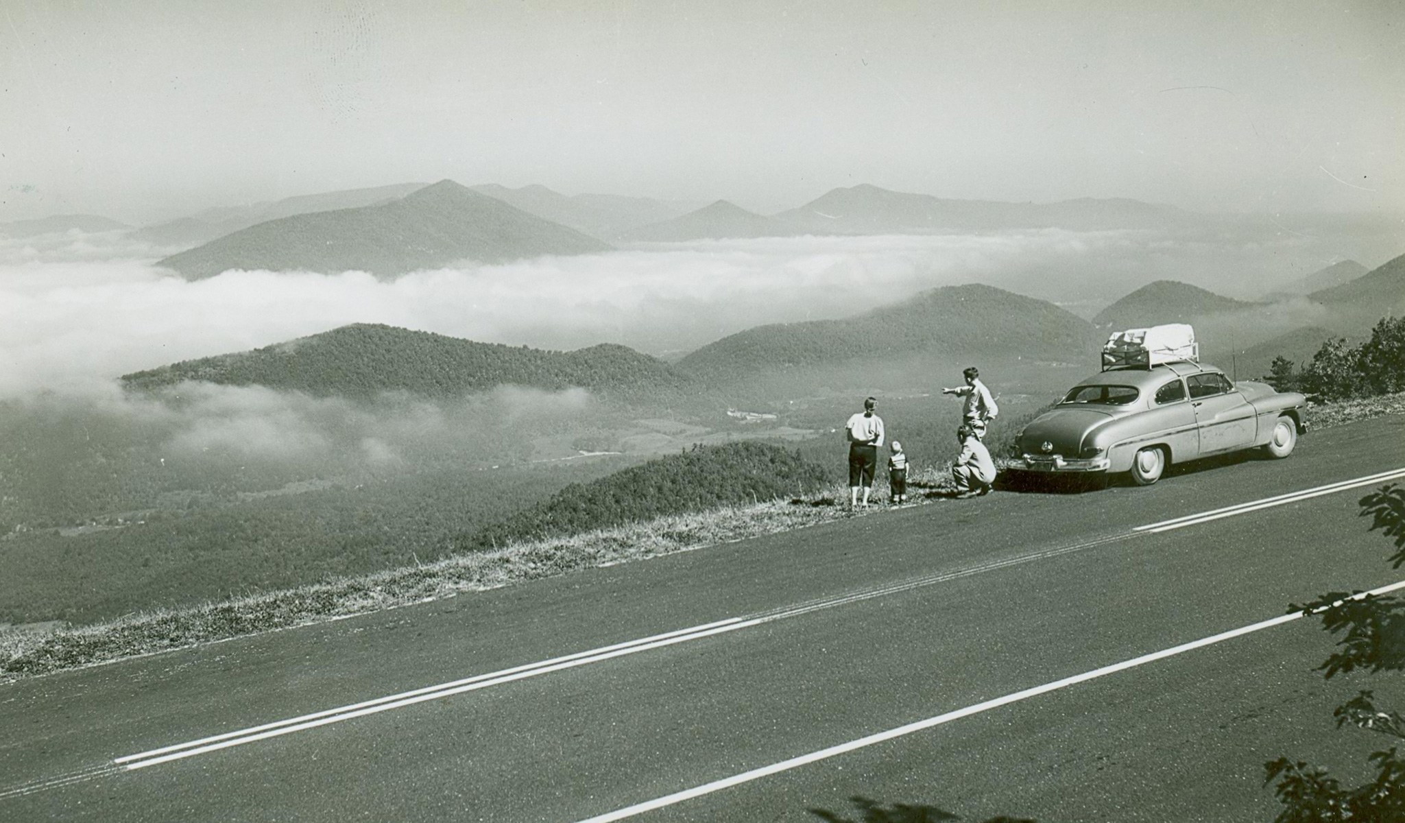 A family in a mid-1900s automobile stopped at an overlook to enjoy the scenery A family in a mid-1900s automobile stopped at an overlook to enjoy the scenery