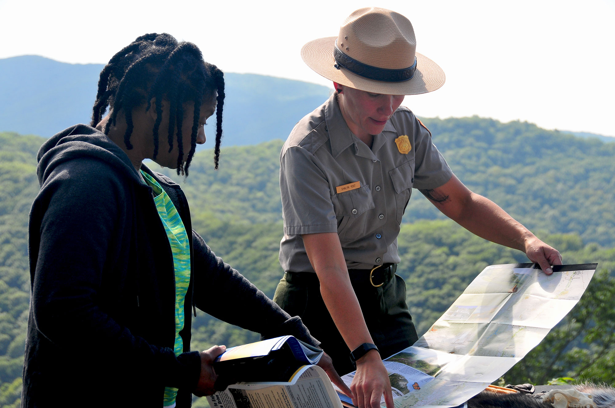 A ranger holding a map provides directions to a woman