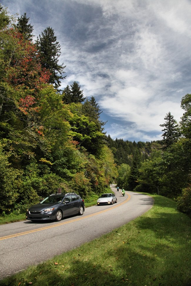 Vehicles drive down a winding road.