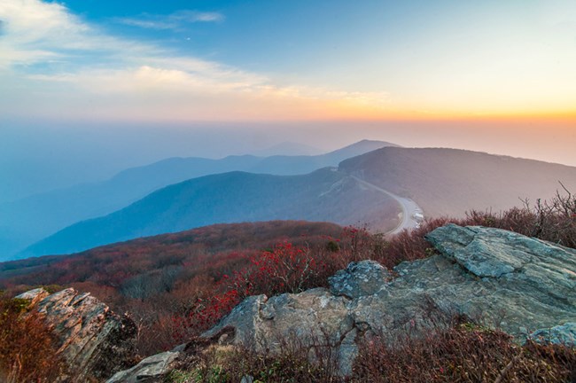 View from the rocky summit of a mountain. Heavy smoke from wildfires hangs in the air, obscuring the view of mountains.