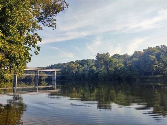View of James River Bridge with the James River passing underneath on a clear day with trees in the background. View of James River Bridge with the James River passing underneath on a clear day with trees in the background.