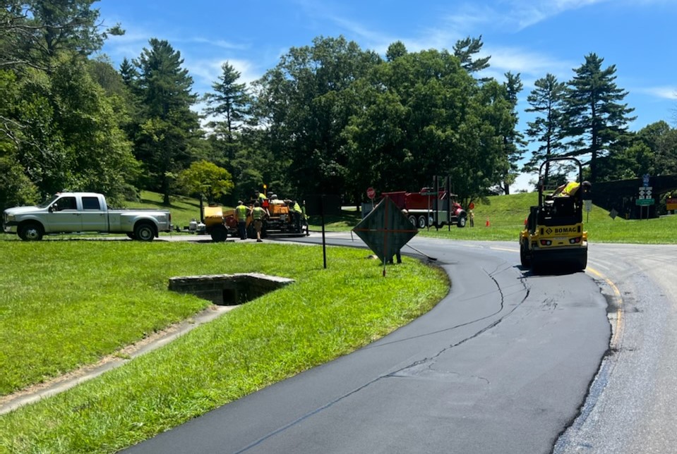 Trucks, equipment and other paving operations underway on a small section of a parkway area.