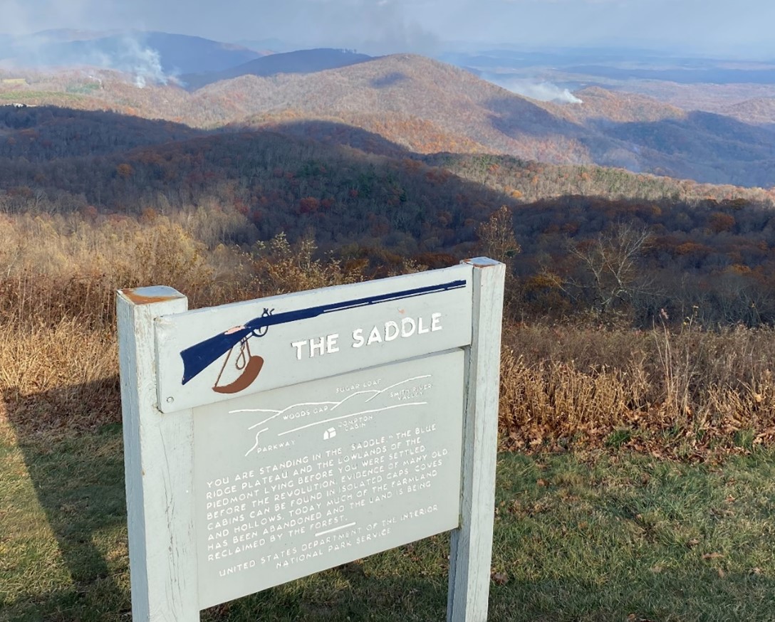 Looking beyond an interpretive sign at milepost 168 on the Blue Ridge Parkway, smoke from the Tuggle’s Gap fire is seen in the distance.