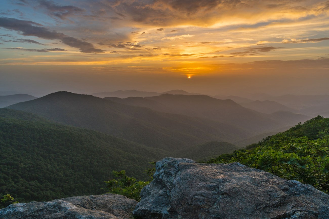 Sunset over lush, green forested mountains