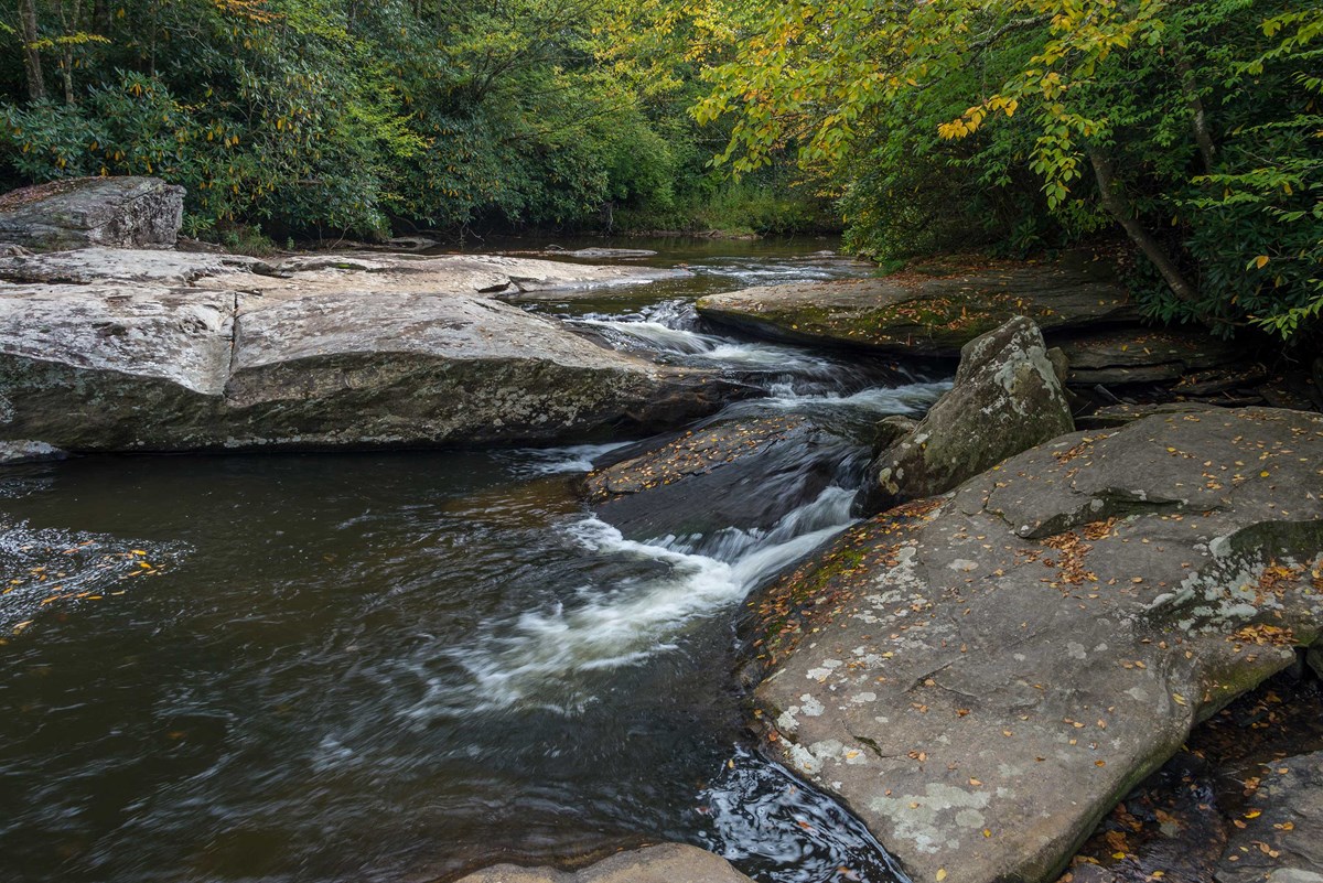 A creek flows between boulders in a small cascade.