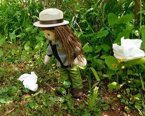 A rag doll dressed like a female park ranger picks up toilet paper wads