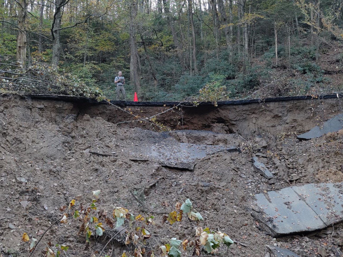 Man standing on a road with the surface partially collapsed