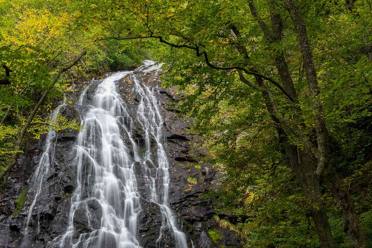 Crabtree Falls Waterfall clinging to rocks surrounded by green trees.