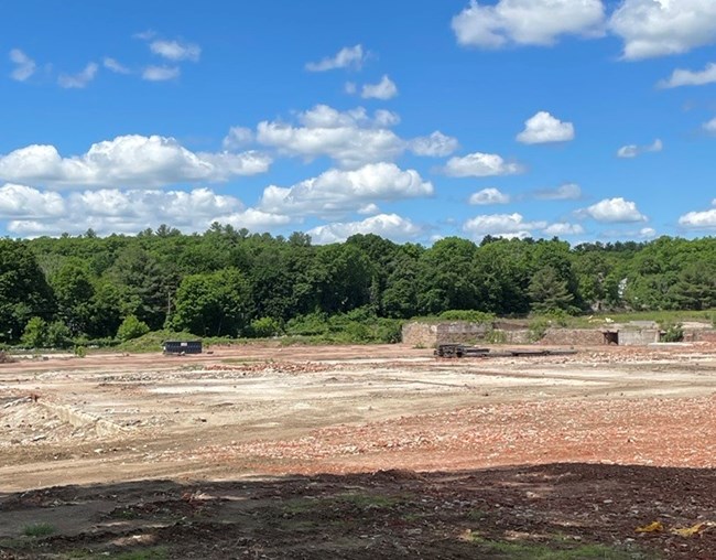 Former site of the Draper Mill. Vacant lot with trees in the distance