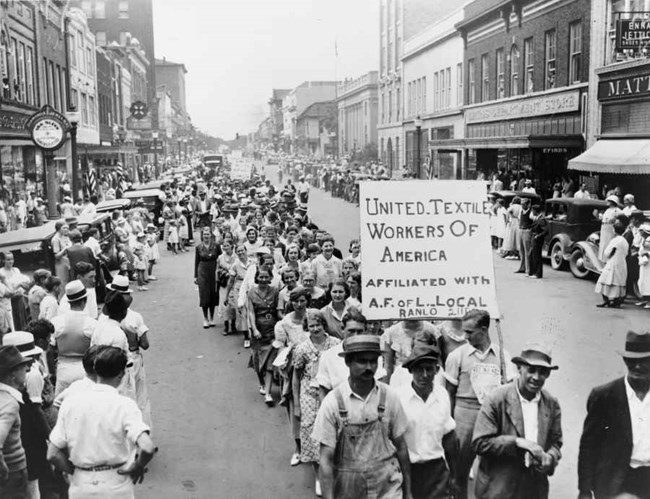 a group of people marching holding signs through a city