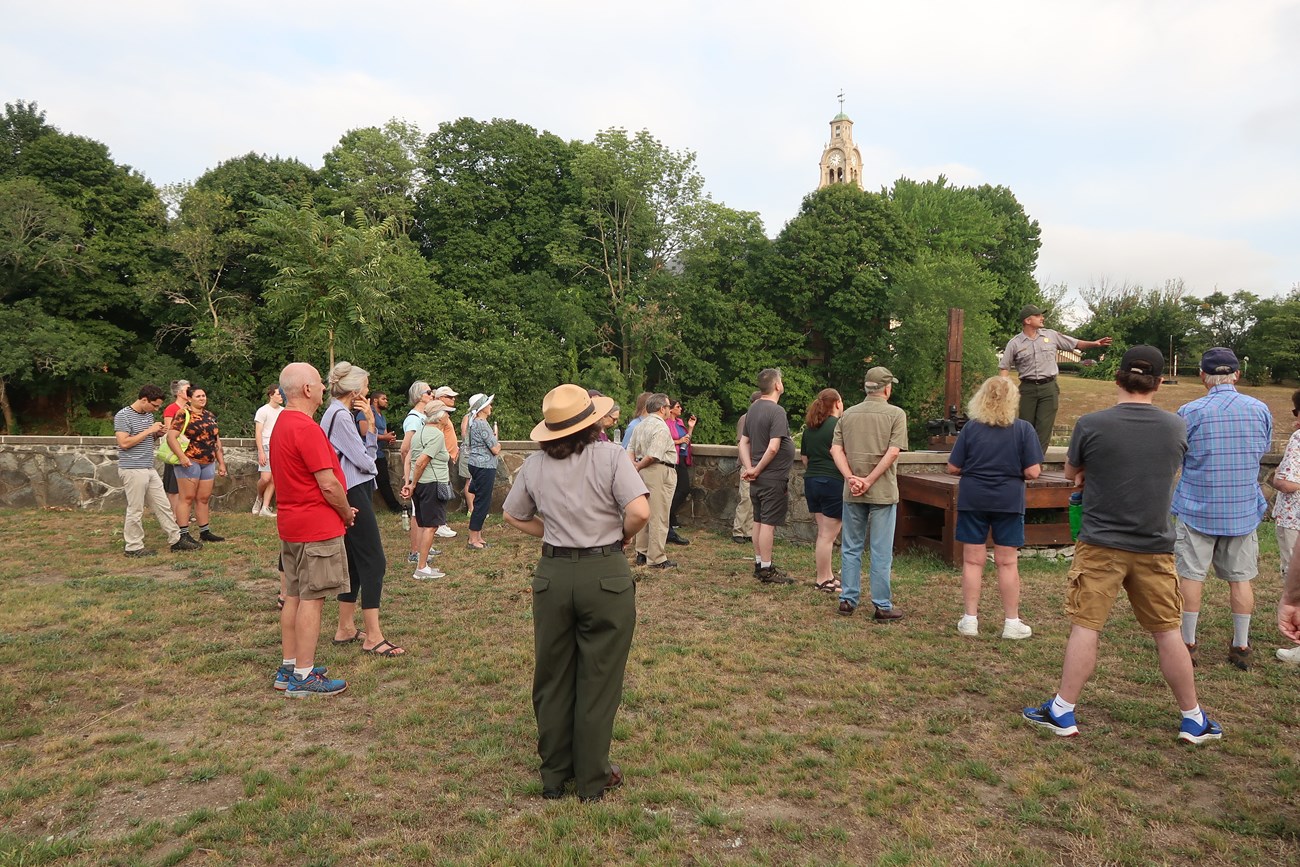 Group of people gathered around wooden platform with Ranger talking